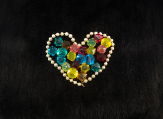 White pearl heart with color gems within on black fur background