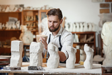 Male craftsman in working uniform makes a limestone copy of woman torso at the creative studio and show making process from start to finish.