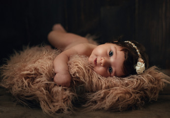 Newborn baby, beautiful infant lies in pink fur blanket on wood background. Two month old. Happy and smiling baby. Copy space