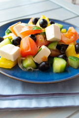 Greek salad with feta cheese, cherry tomatoes, red onion, cucumber, lettuce and black olives. Tasty and healthy meal. Vertical image