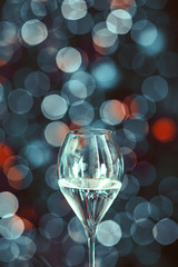 Champagne glass on gray and red shiny bokeh background. Festive glass.