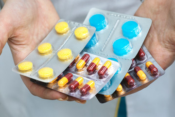 Pharmacist holds pills in his hand against the background of pharmacy shelves
