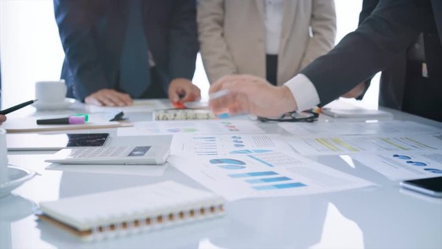 Diverse group of executives having a business meeting. They are discussing over financial data and graphs, showing the development of their company. 