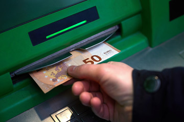 hand of man while withdrawing banknotes 50 euros from an ATM