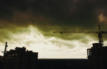 Industrial construction cranes and building site over sunset stormy sky. grunge filter photo 