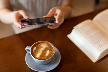 Elegant woman taking photos with smartphone in cafe