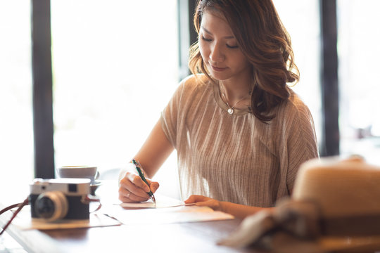 Elegant Woman Writing Postcard In Cafe