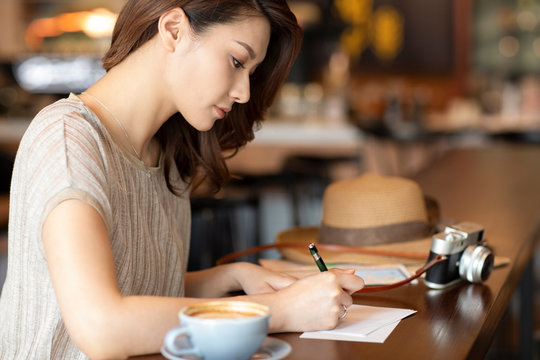 Elegant woman writing postcard in cafe