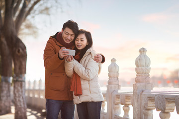 Happy young couple using smartphone outdoors