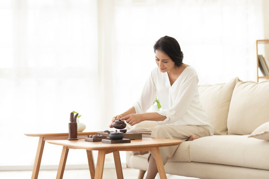 Mature woman drinking tea in living room