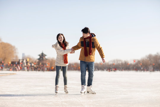 Happy young couple ice skating outdoors