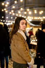 girl in a christmas park looking at the camera. garland background. bright lights