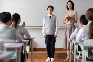 Young teacher introducing a new classmate in classroom
