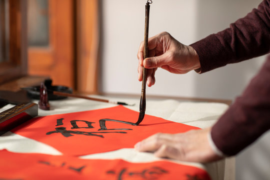 Senior man writing calligraphy on couplets