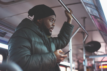 African American man on a bus, going to work in the morning. Everyday man commuting to work by public transport. Handsome man traveling to work. 