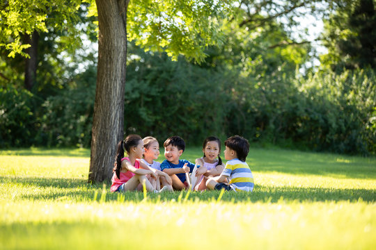 Happy children reading book on meadow
