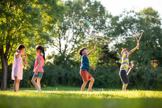 Happy children blowing bubbles on meadow