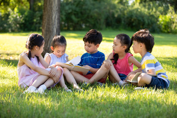 Happy children reading book on meadow