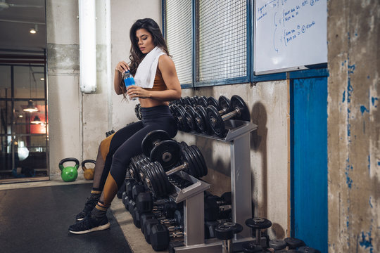 Young sportswoman drinking water in gym