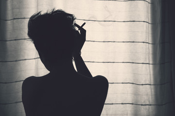 Faceless silhouette of serene woman in front of curtain