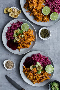 Top View Of Set Of Plates With Healthy Red Quinoa And Delicious Spicy Chicken Curry Garnished With Cut Lime And Banana Chips On Grey Background 