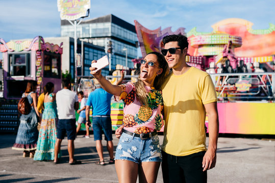 Joyful woman taking selfie with boyfriend on fair