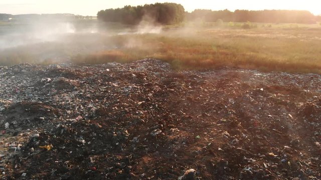 Aerial view of waste garbage dump household pile plastic trash. Burning dump site, smoke clouds, air pollution. Concept environmental struggle with plastic industry.