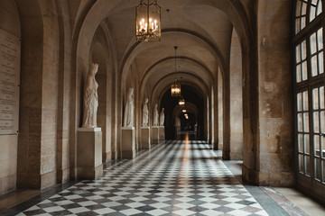 Long passage of palace with sculpture and chandelier with candles in France