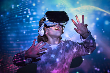 Boy wearing virtual glasses standing in colorful lights