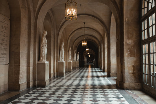 Long passage of palace with sculpture and chandelier with candles in France