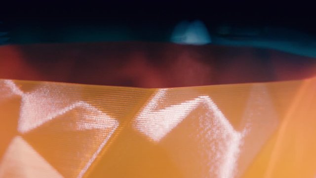 3D-printer is printing layer of an orange object in a close up