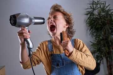 Child in a hairdresser's singing with a hairdryer and a brush
