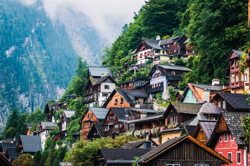 Cozy houses of small settlement located near forest on mountain slope on cloudy day in Austria