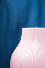 Pink corrugated vase on a classic blue background, fragment, detail. Copy space