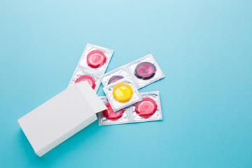 color condom in female hand isolated on a blue background