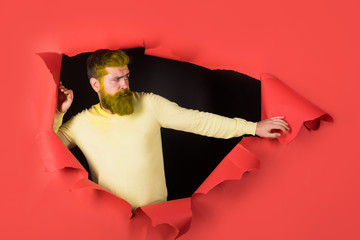 Bearded man through hole in paper. Handsome man making hole in paper. Copy space for advertising....