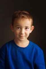 Studio portrait of a boy in a blue classic sweater on a dark background