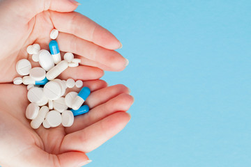 Woman's holding cupped hand full of pills, view from above