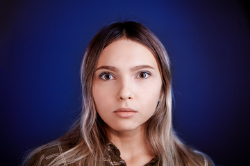Naklejka premium Young woman with wide eyes on a blue background.