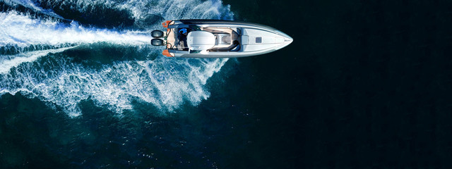 Aerial drone top down ultra wide photo of inflatable speed boat cruising in high speed in deep blue...
