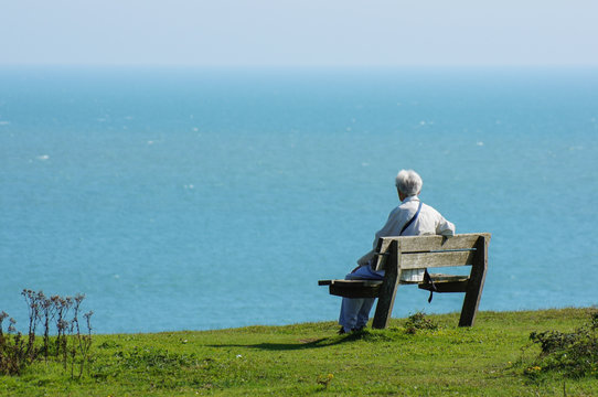 senior man sitting at the bench and looking at the sea - Powered by Adobe