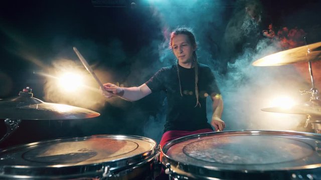 Male Drummer playing drums in smoke. Studio with clouds of smoke and a man playing drums in it
