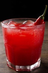 front view glass with red alcoholic drink and pepper, with black background