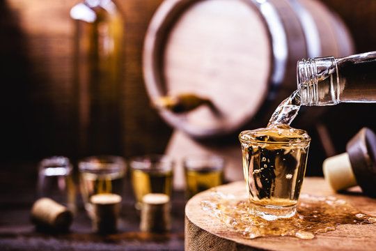 Glass of golden rum, with bottle. Bottle pouring alcohol into a small glass. Brazilian export type drink. Brazilian product for export, distilled drink known as brandy or pinga. Day of cacha&ccedil;a.