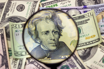 Twenty usa dollar bill inspected under a magnifying glass. Financial concept, money background.
