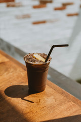 Iced chocolates topped with chocolate flakes and oranges on a wooden table in this café
