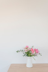 シンプルな花瓶とピンク系の花　ピンク系の花とグリーン　部屋　白壁　白背景　室内　屋内　自然光　余白　ホワイトスペース　コピースペース　文字スペース　縦　背景素材　背景　グラフィック素材　　白　緑　ピンク　春　季節　スイートピー