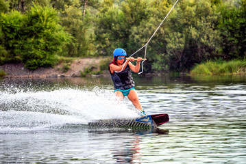 Girl wakeboarding on river lake sea on summer spring day in jacket