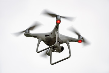 White drone quadcopter taking off from the ground on white background, isolated.