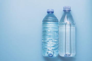 Naklejka premium Two different plastic bottles with a sparkle of water on a blue background. Copyspace, place for text, flat lay